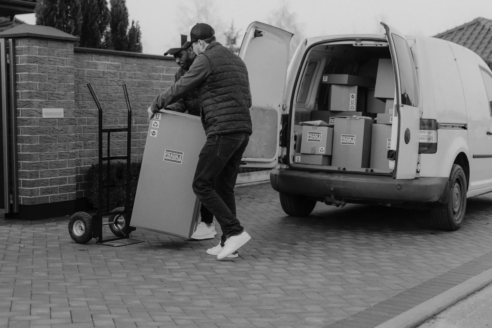 Dos repartidores descargando una caja grande de una furgoneta